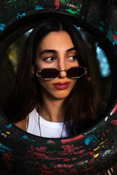 בחורה_עם_משקםי_שמש_מציצה_מתוך_צמיג_ישן_של_מכונית_בוק