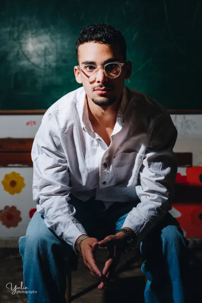 בחור_בחולצה_לבנה_יושב_על כיסה_בכיתה_צילומים_אישיים