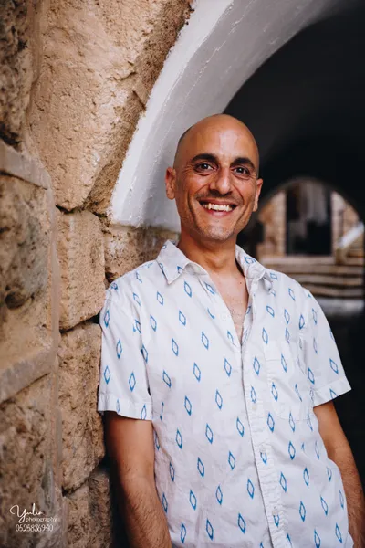 גבר_מחייך_עומד_ליד_קיר_לבנים_ביפו_העתיקה_בוק_אישי