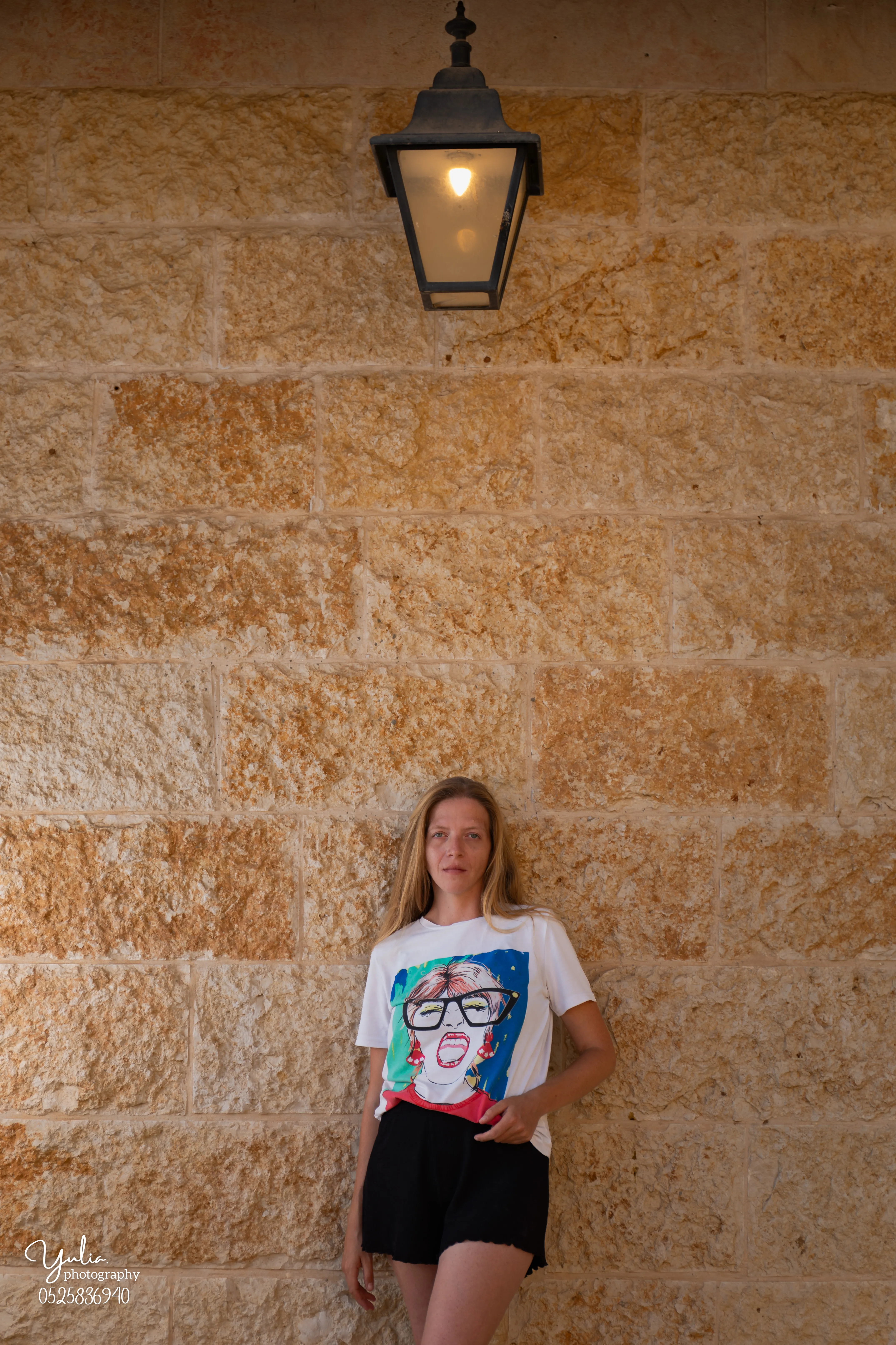 אישה תחת פנס על קיר אבן