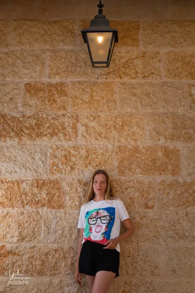 קיר_לבנים_צהובות_עם_מנורה_ישנה_למעלה_בחורה_עומדת_מתחת_בוק_אישי