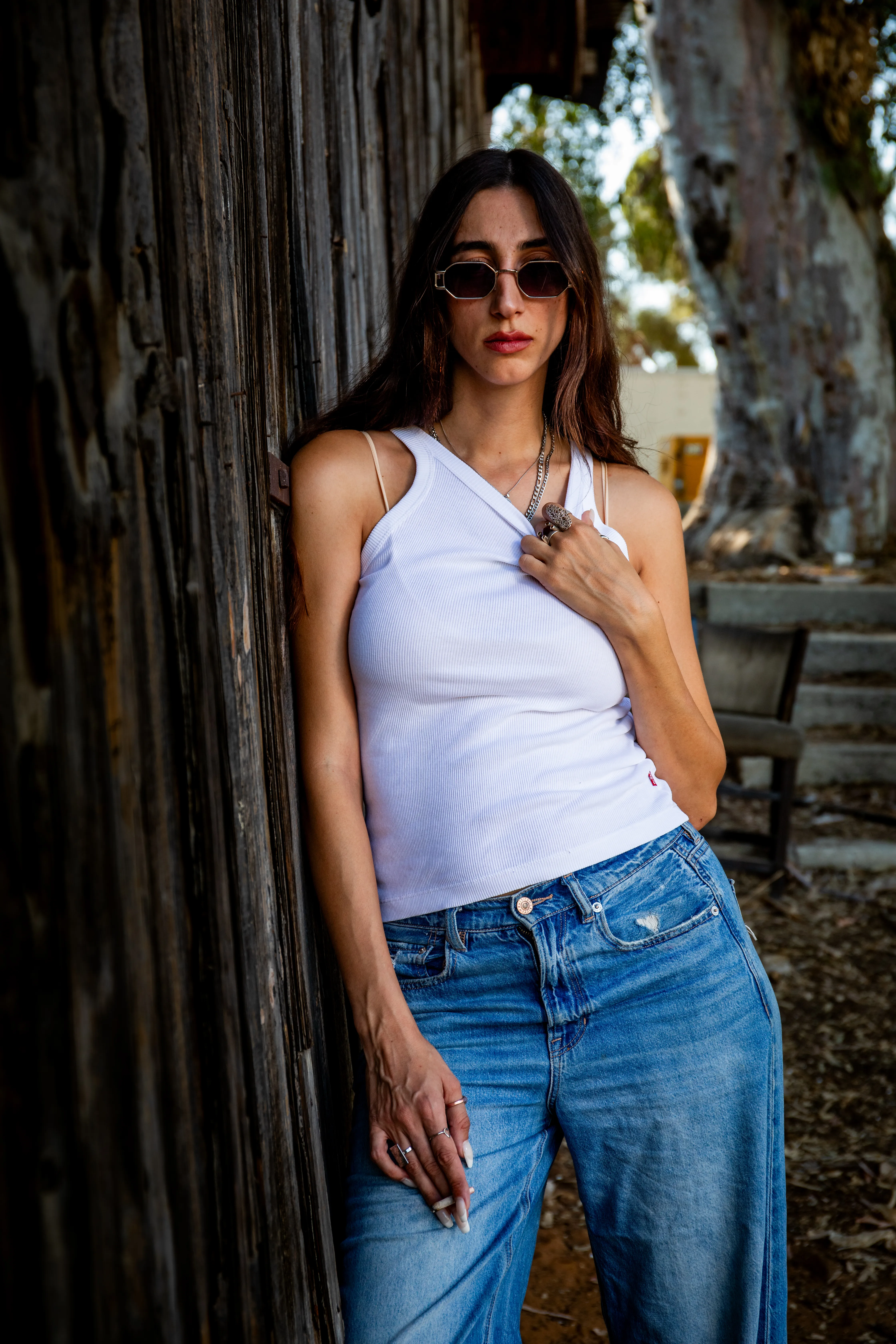 בחורה בחולצה לבן נשענת על קיר עצים בוק אישי
