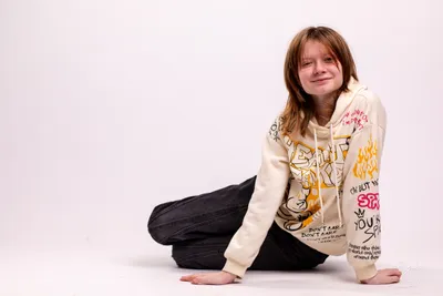 בחורה_יושבת_על_הריצפה_על_רקע_לבן_בסטודיו_צילומי_תדמית